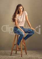 You have what it takes. Studio shot of a beautiful young woman sitting on a stool against a plain background.