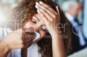 Yes I definitely have a fever. Closeup of a frustrated businesswoman using a tissue to wipe her nose while being seated in the office.