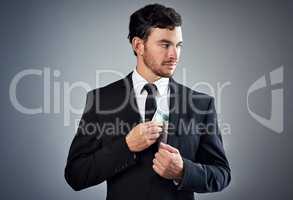 Making money without morals. Studio shot of a young businessman concealing money in his jacket against a gray background.