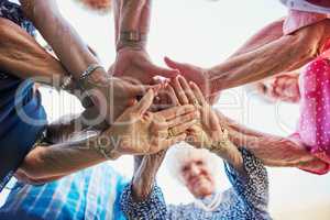 Do not tire when you retire, get inspired. Low angle shot of seniors hands huddled together outside.