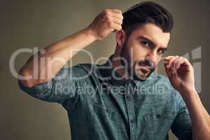 Beard season is here. Studio shot of a handsome young man combing his hair against a grey background.