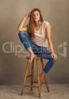 Darling, youre different. Studio shot of a beautiful young woman sitting on a stool against a plain background.
