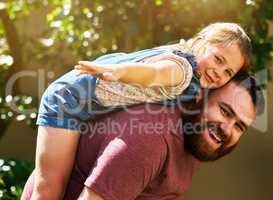 With dads support shell fly far. an adorable little girl enjoying a piggyback ride from her father in their backyard.