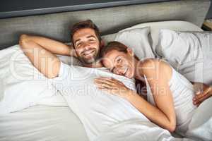 We all love a bit of laziness. a happy young couple relaxing in bed together at home.