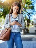 Im just around the corner. an attractive young woman using her cellphone while commuting to work.