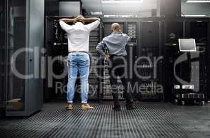 Meanwhile, in the server room...Rearview shot of two IT technicians having difficulty repairing a computer in a server room.