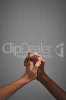 Friendship can cross any barrier. Studio shot of unidentifiable hands holding on to each other against a gray background.
