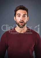 Mind. Blown. Studio shot of a handsome young man looking surprised against a gray background.