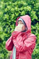 It feels great to blow my nose. a young woman blowing her nose with a tissue outdoors.