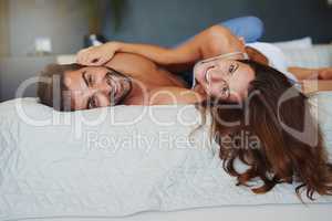 We can make just staying in bed seem like fun. a playful couple relaxing in bed together.