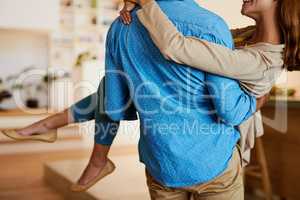 Its a long held tradition. Rearview shot of a young man carrying his wife through their home.