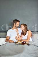 Rise and shine then wine and dine. a happy young couple enjoying breakfast in bed together at home.