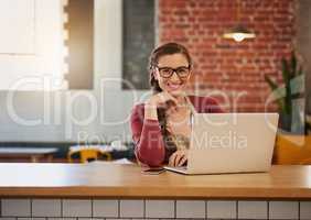 I turned my coffee shop into a wifi hotspot. Portrait of a happy young business owner doing admin at a table in her coffee shop.