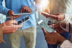 Conferencing in the age of wireless technology. an unidentifiable team of businesspeople using their wireless devices in a huddle in the office.