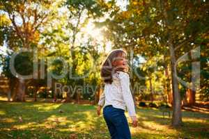 Kids make every moment spectacular. a happy little girl playing in the autumn leaves outdoors.