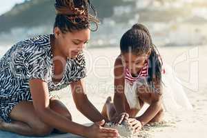 Childrens creativity thrive in open-ended play, like building sandcastles. a mother and her little daughter building a sandcastle together at the beach.