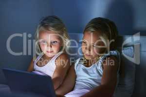 Watching their favourite cartoon before bedtime. two little girls using a digital tablet before bedtime.