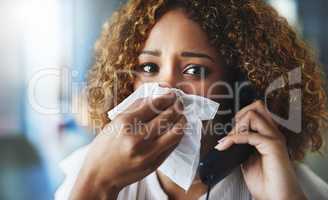 Someone call a doctor. a frustrated businesswoman blowing her nose and answering the phone while being seated in the office.