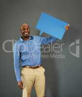 Smiling, african american male voter holding a copyspace board sign on public opinion message. Casual and positive man holding a social media speech bubble or communication icon for news poll idea