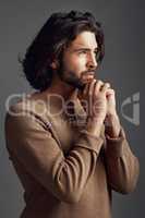 How am I going to get through this. Studio shot of a handsome young man praying against a gray background.
