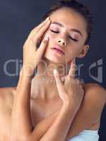 Being comfortable with yourself brings clarity to the mind. Studio shot of an attractive young woman posing and touching her face on two different places while her eyes are closed.