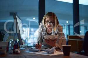 The hours she puts in will ensure her success. a businesswoman working on a digital tablet in her office late into the night.