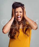 Hear me roar. Studio shot of an attractive young woman shouting against a grey background.