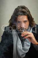Cutting back on my nicotine intake. a stylishly dressed man smoking an electronic cigarette while sitting in the studio.