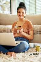 Hot coffee, hotspot and shopping all while at home. a beautiful young woman using a laptop and credit card at home.