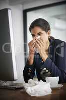 Colds are only temporary. a young frustrated businesswoman blowing her nose and working in the office.
