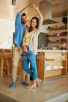 Dancing joyfully. Full length shot of an affectionate young couple dancing in their kitchen.