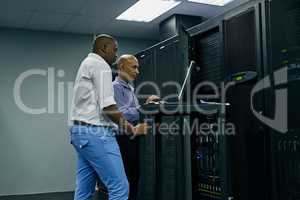 System administrators to the rescue. two IT technicians using a computer while working in a data center.