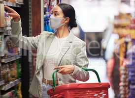 Supermarket, shopping and customer with covid face mask in retail store for food, groceries or product from shelf. Young woman with basket during inflation price increase or sales choice on grocery