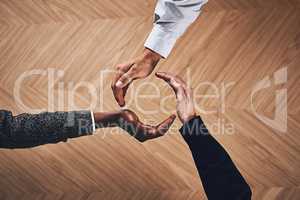 Teamwork creates a continuous circle of success. High angle shot of a group of unidentifiable businesspeople forming a circle with their hands.