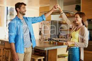 Hes taking the lead. an affectionate young couple dancing in their kitchen.