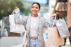 Woman shopping, fashion and retail gift bags for customer buying stylish clothes and spending money on a city spree. Portrait smile, happy and fun lady with cool, trendy and sales presents from store