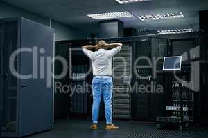 Behind the scenes of an error message. Rearview shot of an IT technician having difficulty repairing a computer in a data center.