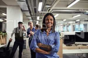 Impressive work is simply what we do. Portrait of a young designer standing in an office with her colleagues in the background.