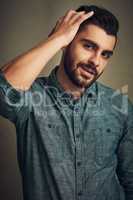 Wear your beard with style. Studio shot of a handsome young man posing with his hand in hair.